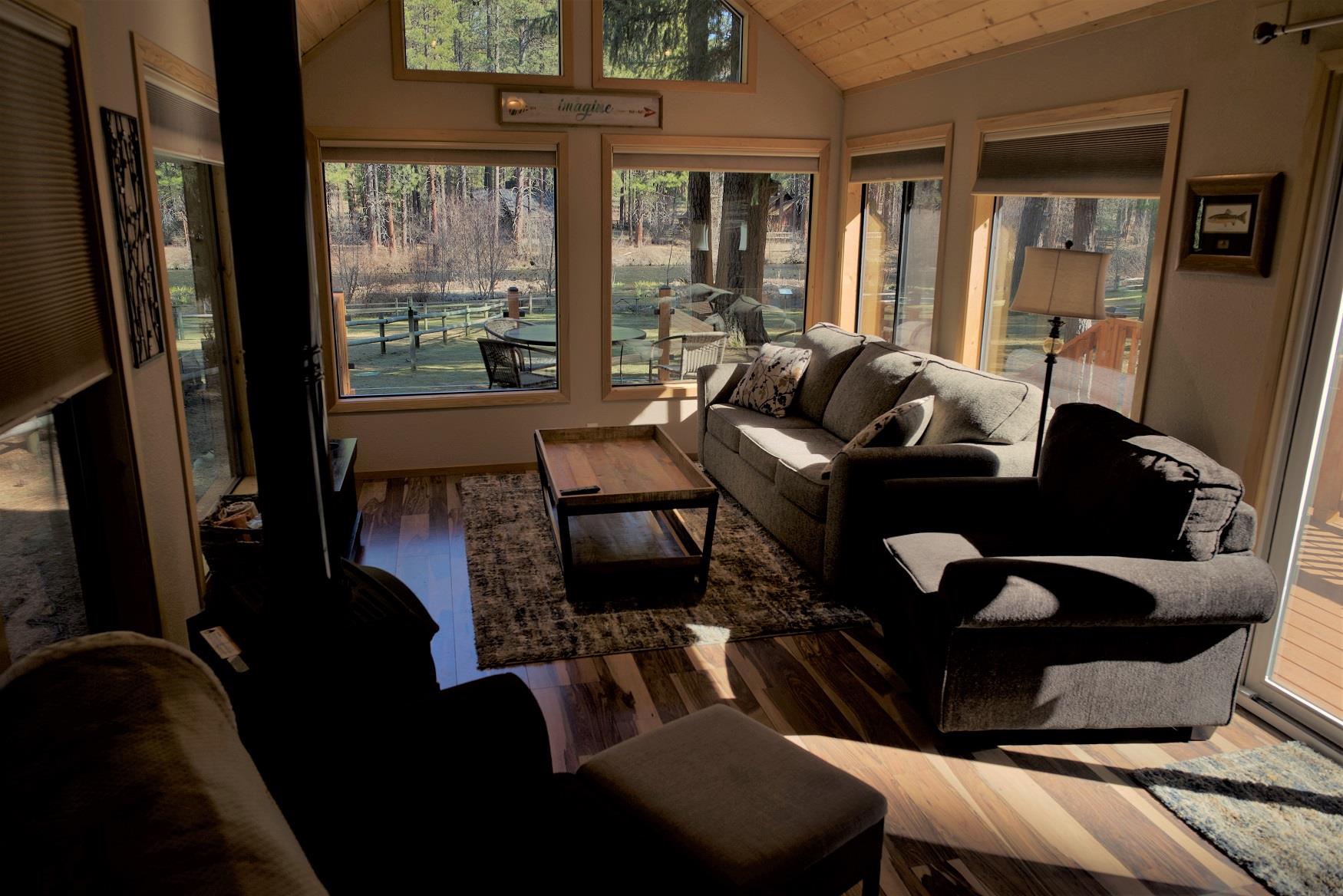 Curl up in front of the fire in the living room of Riverview Cabin, with a perfect view of the Metolius River out the gigantic windows, at Cold Springs Resort and RV Park in Camp Sherman, Oregon 