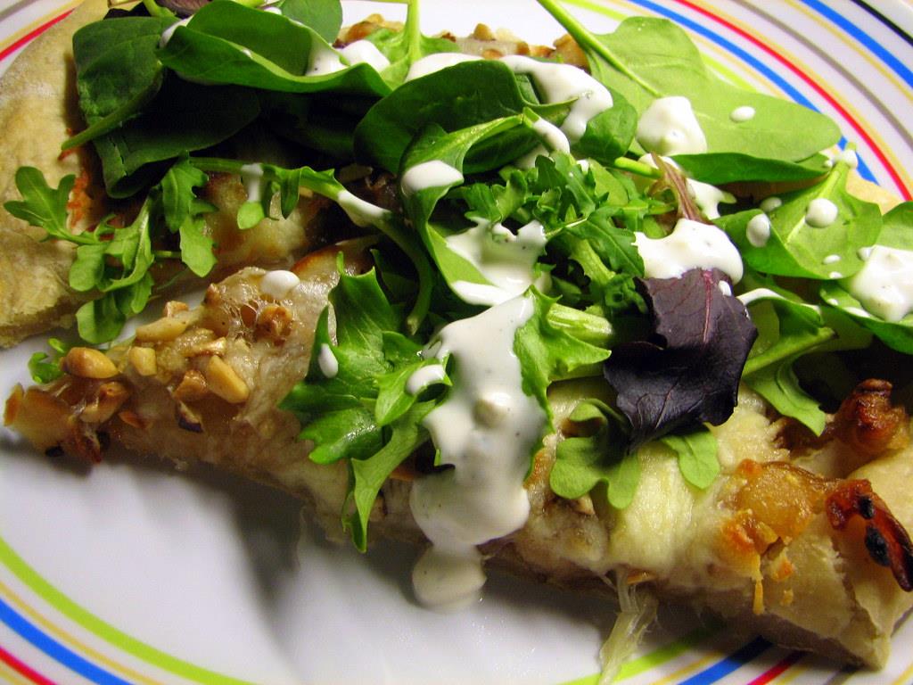 Close-up of a slide of pizza covered with green salad